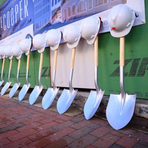 Hardhats leaning on shovels at The Cooper development site